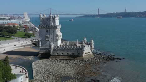 Aerial-view-of-Belem-Tower-fortified-tower-located-in-the-civil-parish-of-Santa-Maria-de-Belem-in-Lisbon-Portugal-reveling-the-25-De-Abril-Bridge