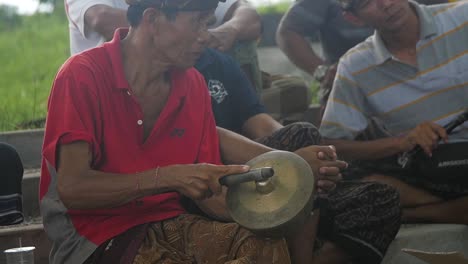 Vista-Panorámica-En-Cámara-Lenta,-Músicos-Balineses-Sentados,-Tocando-Instrumentos-De-Percusión-De-Oro-En-Grupos-Juntos