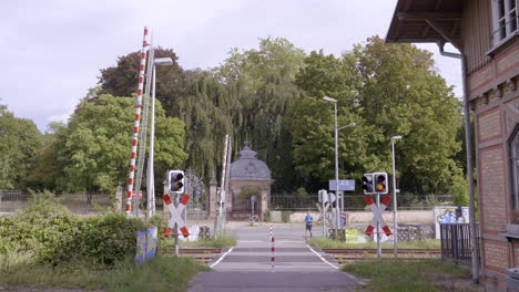 Jogger-walks-trough-railroad-crossing-with-barrier-and-red-traffic-light,-Darmstadt,-Hessen,-Germany