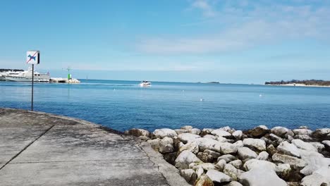 Bote-Pequeño-Saliendo-Del-Puerto-Deportivo-Contra-El-Cielo-Azul-Con-Nubes-Cerca-Del-Parque-De-Camping-Polidor,-Croacia