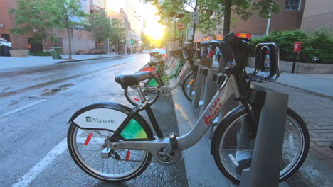 Editorial,-outdoor-view-of-public-bikes-station,-bike-share,-,-in-street,-people-and-cars-passing,-sunset-moments