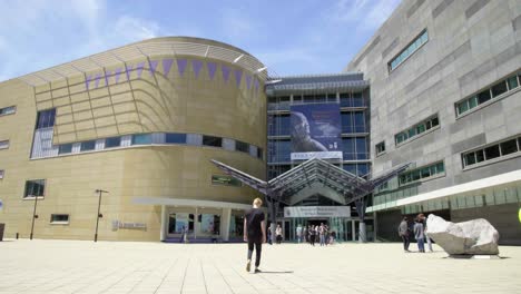 A-low-angle-view-of-the-Te-Papa-museum-in-Wellington,-NZ,-with-lots-of-people-walking-around-in-front-of-the-building