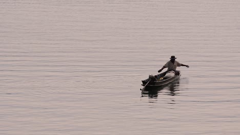 Fisherman-silhouetting-as-he-is-casting-and-drawing-his-net-in-the-River-before-dark,-in-slow-motion