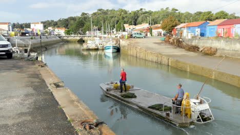 Oyster-farmers-returning-in-the-morning-to-the-port-of-Saint-Trojan-les-Bain-in-a-flat-bottomed-boat,-island-of-Oleron
