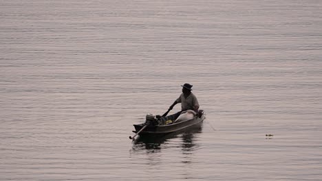 Fisherman-silhouetting-as-he-is-casting-and-drawing-his-net-in-the-River-before-dark,-in-slow-motion