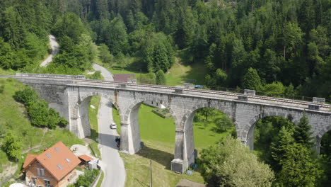 Aerial-pull-out-tilt-up-shot-for-old-railway-bridge-with-arches-in-the-countryside-in-Ravne-na-koroskem,-Slovenia