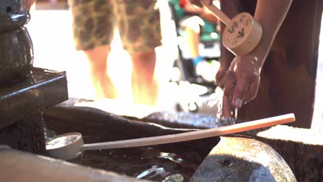 Guy-wearing-a-Yukata-washing-his-hands-the-traditional-way-in-Kyoto,-Japan-soft-lighting-slow-motion-4K