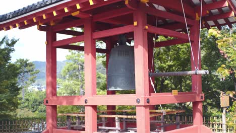 Ancitent-traditional-bell-sitting-outside-of-an-old-temple-in-Kyoto,-Japan-sunny-day-medium-shot-4K