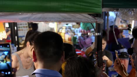 Grupo-De-Personas-Grabando-A-Una-Hermosa-Mujer-Caliente-En-Un-Puesto-De-Mercado-De-Comida-Callejera,-Tailandia