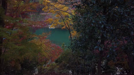 Autumn-colors-in-Kyoto,-maples-framing-blue-waters-of-river-in-background