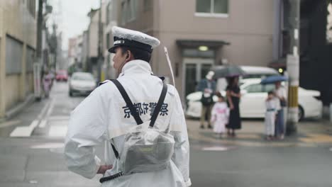 Vista-Trasera-De-Un-Policía-Japonés-En-La-Calle-Vestido-Con-Un-Impermeable-En-Un-Día-Lluvioso-En-Kyoto,-Japón