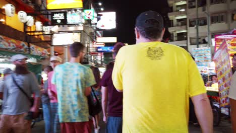 Handheld-scenes-of-the-tourists-are-walking-around-Khao-San-Road-at-night-time-famous-which-each-year-tourists-from-many-countries-came-to-visit-in-Bangkok,-Thailand