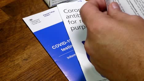 Male-reading-NHS-corona-virus-antibody-self-test-kit-contents