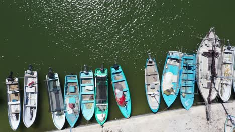 Aerial-view-looking-straight-down-and-camera-sliding-to-the-left-showing-small-wooden-fishing-boats-in-a-harbor-in-Mexico