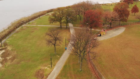 a-bird's-eye-view-over-a-person-walking-along-a-paved-walkway,-on-a-cloudy-day-in-Flushing-Meadows-Corona-Park,-NY