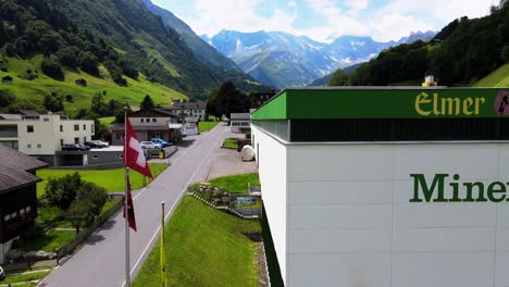 Toma-Aérea-Del-Logotipo-De-La-Planta-De-Agua-Mineral-Elmer-En-Elm,-Glarus,-Suiza