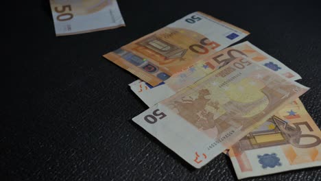Eine-Nahaufnahme-Von-Euro-Banknoten,-Die-Auf-Eine-Schwarze-Oberfläche-Fallen