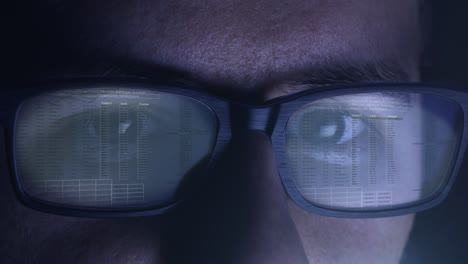 Man-works-at-night-on-computer-screen,-which-is-reflected-on-his-glasses---code,-numbers,-network---Close-up