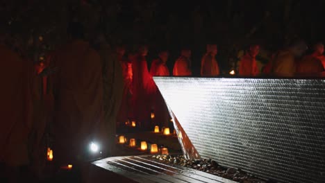 Medium-Exterior-Shot-of-Monks-Lining-Up-Near-Water-Feature-at-Night
