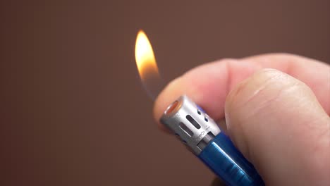 Male-hand-ingniting-gas-lighter-with-forefinger,blurred-background