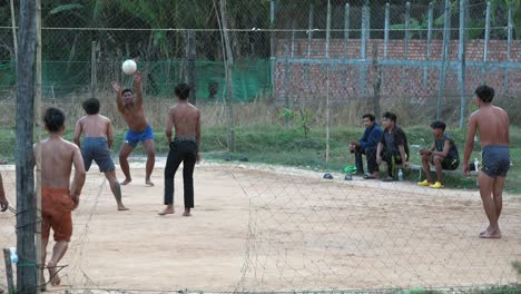 Medium-Exterior-Static-Shot-of-Volleyball-Players-With-Man-Exit-with-a-Net-Cut-Through-as-Door-in-the-Day