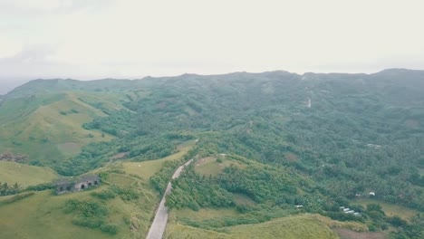 Cinematic-aerial-drone-view-of-a-picturesque-landscape-of-ocean-meeting-mountains-in-Batanes,-Philippines