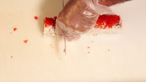 Top-View-Of-A-Sushi-Roll-Being-Cut-Into-Pieces-With-A-Sharp-Knife---overhead-shot,-slow-motion