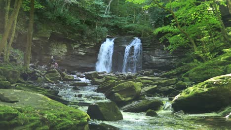 Un-Hombre-Y-Una-Mujer-Jóvenes-Se-Sientan-Junto-A-Seneca-Falls,-Una-Gran-Cascada-Ubicada-A-Lo-Largo-De-Seneca-Creek,-Dentro-Del-área-Recreativa-Nacional-De-Spruce-Knob-seneca-Rocks-En-Virginia-Occidental