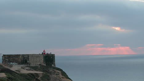 Zeitraffer---Menschen-Besuchen-Den-Leuchtturm-Von-Nazare-Bei-Sonnenuntergang-In-Der-Nähe-Des-Nordstrandes-In-Portugal