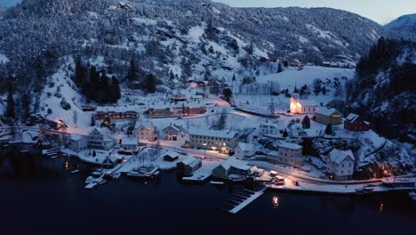 Antena-De-La-Pequeña-E-Idílica-Aldea-Noruega-Stamnes-Al-Atardecer-Durante-El-Invierno---Luces-De-La-Calle-E-Iglesia-En-Un-Paisaje-Helado