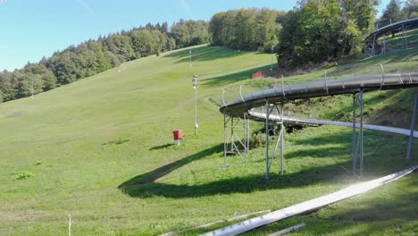 Drohnenaufnahme-Einer-Langen-Metallrutsche-Auf-Einem-Hügel-An-Einem-Sonnigen-Tag