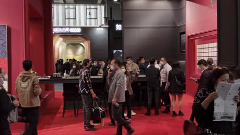 People-wearing-masks-and-walking-inside-product-pavilion-at-kitchen-design-exhibition-in-China,-during-COVID-19-Pandemic