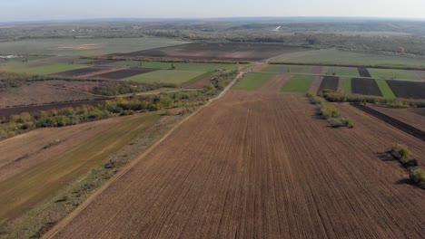 Aerial-view-of-farmlands-and-roads,-sunny,-autumn-day---tilt-up,-drone-shot