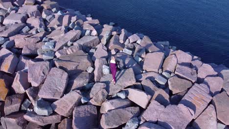 Aerial-young-women-standing-on-rocks-near-coastline