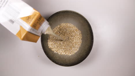 Pouring-Juice-Into-A-Bowl-With-Oats---High-Angle,-Static-Shot
