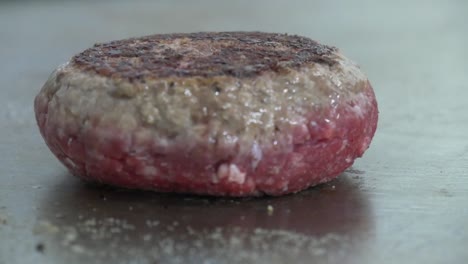Close-up-of-a-flipped-hamburger-patty-being-placed-back-on-a-restaurant-grill-to-cook