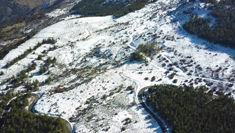 Luftaufnahme-Einer-Straße-Und-Des-Waldes-Auf-Einem-Verschneiten-Berg