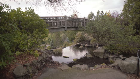 Bridge-over-small-pond-with-duck-in-Victoria-park,-Vancouver-on-cloudy-day