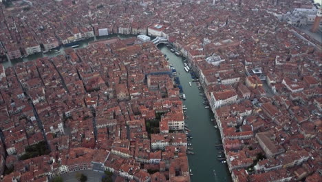 Wide-aerial-shot-of-Canal-Grande-and-flying-towards-Ponte-di-Rialto-from-above-at-dusk,-Venice,-Italy