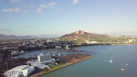 Drone-panning-right-to-left-revealing-Townsville-city-with-Castle-Hill-in-the-background-on-a-sunny-morning