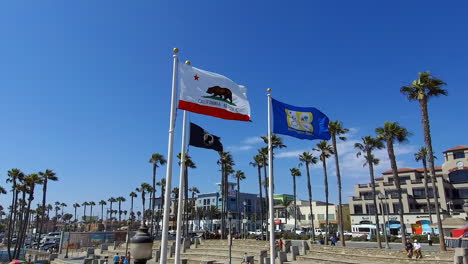 slow-motion-footage-of-the-California-state-flag,-MIA-POW-flag,-and-the-Huntington-Beach-City-flag-flying-in-Huntington-Beach-California