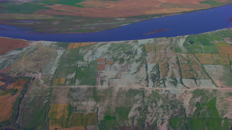 Blue-river-going-from-from-the-farms,-Aerial-view,-Roads-and-trees-spread-in-the-crafted-farms
