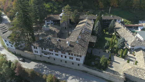 Aerial:-a-car-passes-alongside-the-Troyan-Monastery-in-the-woods-of-Bulgaria