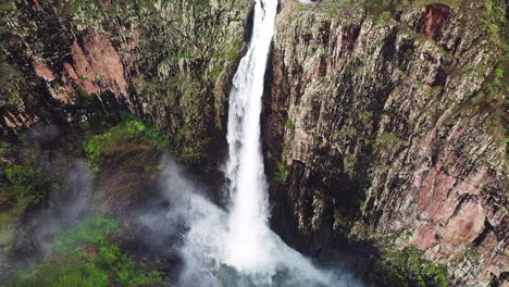 Drone-flys-backwards-while-camera-looks-up-to-show-huge-waterfall