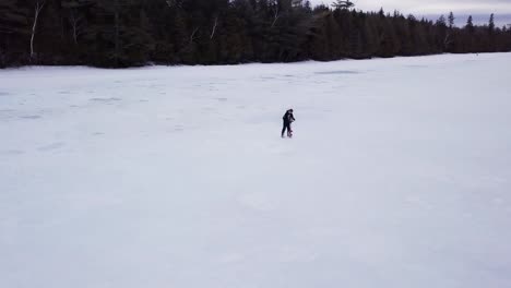 Ein-Mann-Bohrt-Mit-Einer-Schnecke-Ein-Loch-Zum-Eisfischen-Am-Fitzgerald-Pond,-Maine