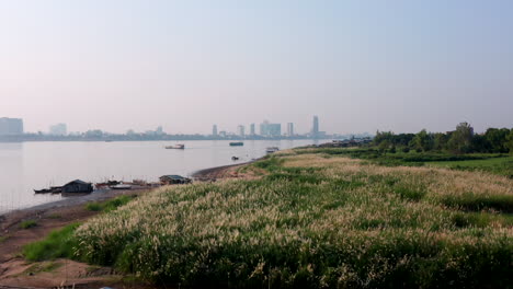 Aerial-drone-footage-flying-over-the-Mekong-shore-and-revealing-Phnom-Penh-on-the-background