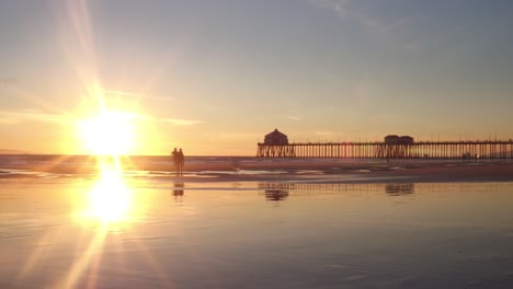 A-4k-sunset-time-lapse-of-a-family-enjoying-themselves-at-the-beach-low-tide-with-the-pier-in-the-background