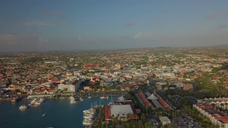 Aerial-pan-view-of-the-island-with-a-zoom-into-the-marina-with-a-boat-sailing-4K