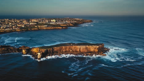 Greatness-from-the-sky-showing-rising-sun-through-an-aerial-view-at-Papôa,-Peniche,-Portugal