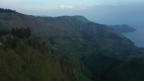 Aerial-drone-footage-of-the-green-valleys-and-cliffs-above-Lake-Toba-in-the-Karo-Regency-of-North-Sumatra,-Indonesia
